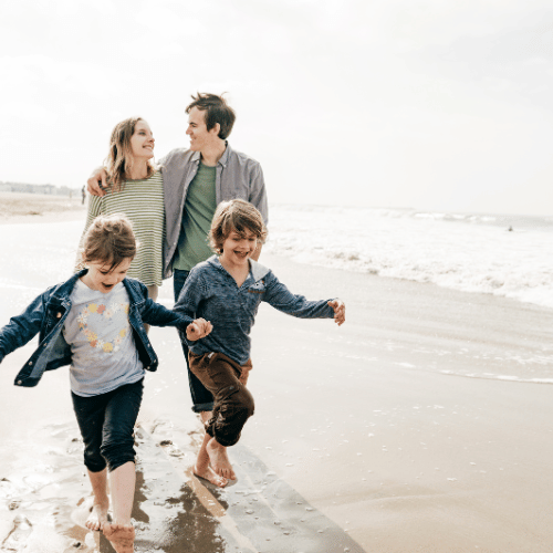 A family of four walking along the beach.